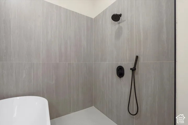 Primary Bathroom. Matte black shower fixtures, tiled shower surround, textured wall tiles, and white hexagonal shower floor tiles