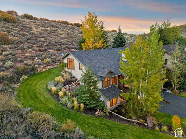 Multi-level residence with a dark shingle roof, stone accents, and varied siding