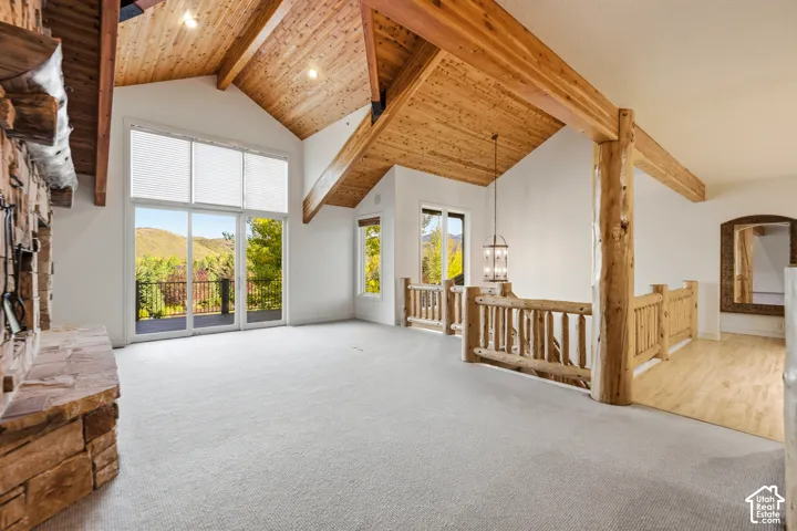 Vaulted wood-paneled ceiling with exposed beams, large stone fireplace, and expansive sliding glass doors