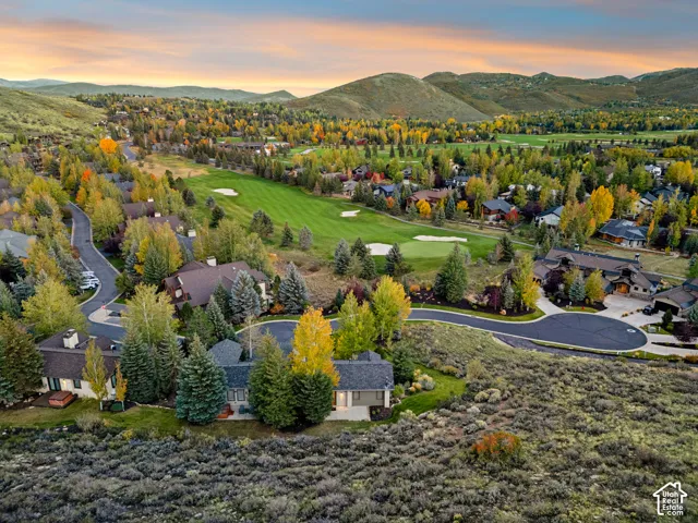Expansive residential area featuring a golf course, surrounding homes, mature trees, and mountainous terrain