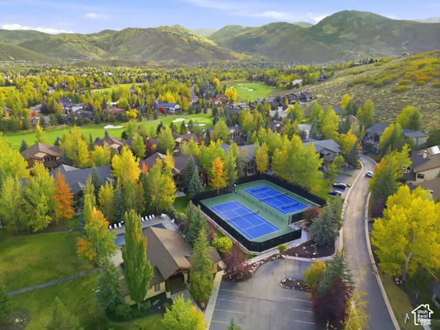 Community with multiple tennis courts, a swimming pool, and golf course access, surrounded by mature trees and mountain scenery