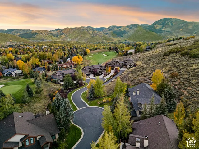 Mountainous terrain surrounding a residential area, featuring winding paved roads, mature trees, and a golf course
