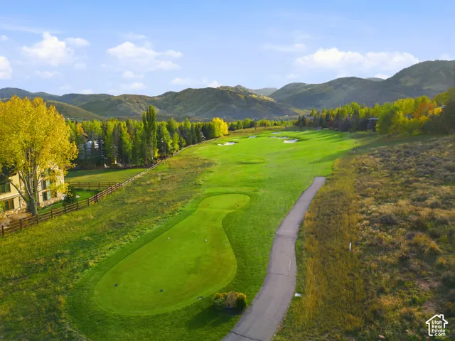 Expansive golf course frontage with a manicured green and paved cart path