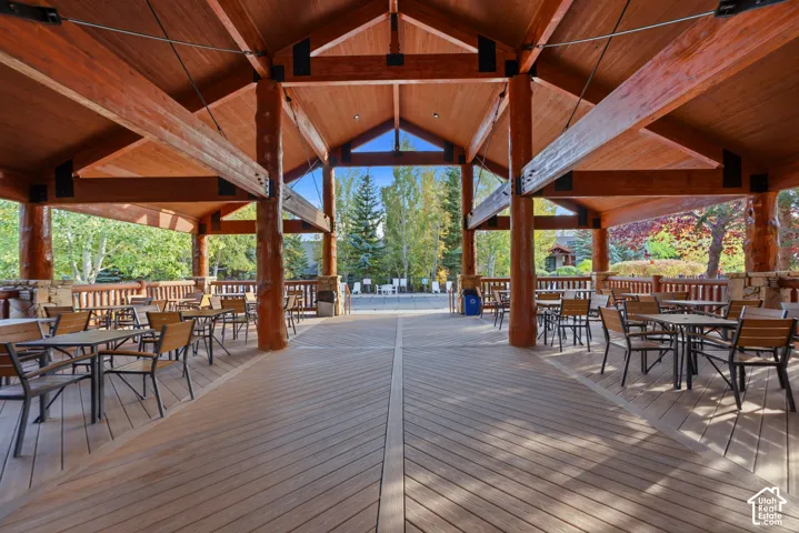 Expansive covered outdoor space with exposed timber beams, a wood-finish vaulted ceiling, and a stone-clad half-wall