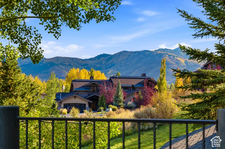 Mountain backdrop, lush landscaping, multi-level dwelling, attached garage, wrought iron railing