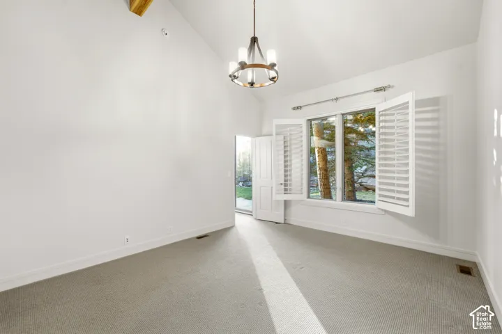 Vaulted ceiling with exposed wood beam, integrated ceiling light fixture, plantation shutters, and direct outdoor access