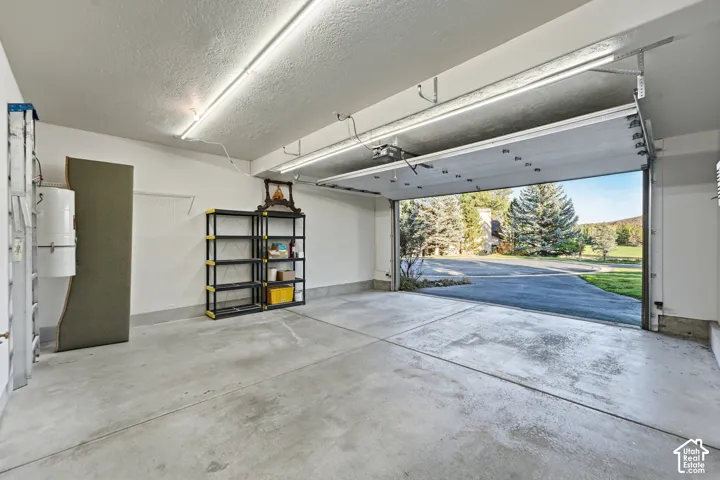Concrete flooring, overhead fluorescent lighting, white painted walls, and an automatic garage door opener