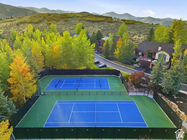 Two outdoor tennis courts with blue playing surfaces and green surrounds
