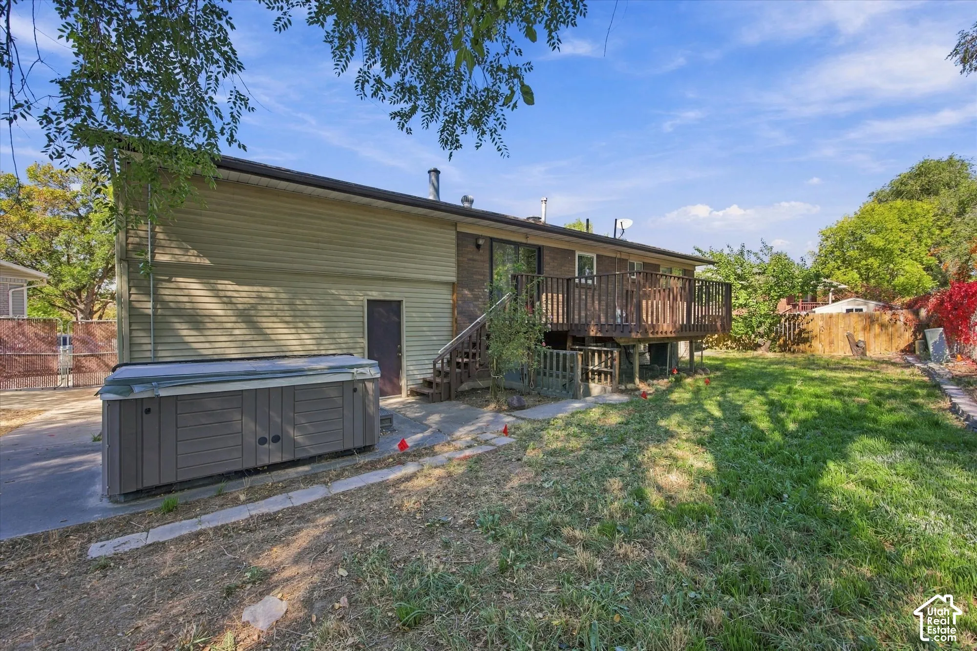 Rear exterior featuring a wood deck, sliding glass door, and a spa area