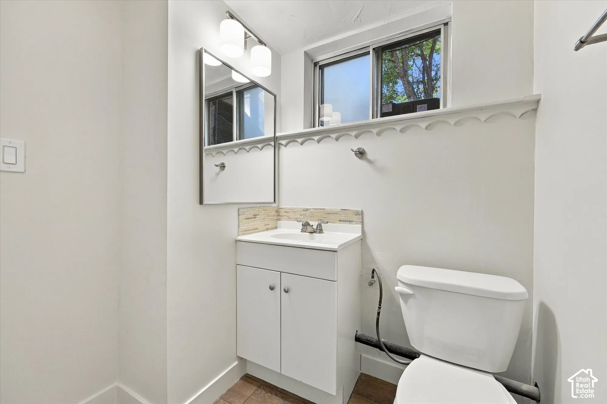 Vanity with white cabinetry, rectangular sink, and mosaic tile backsplash