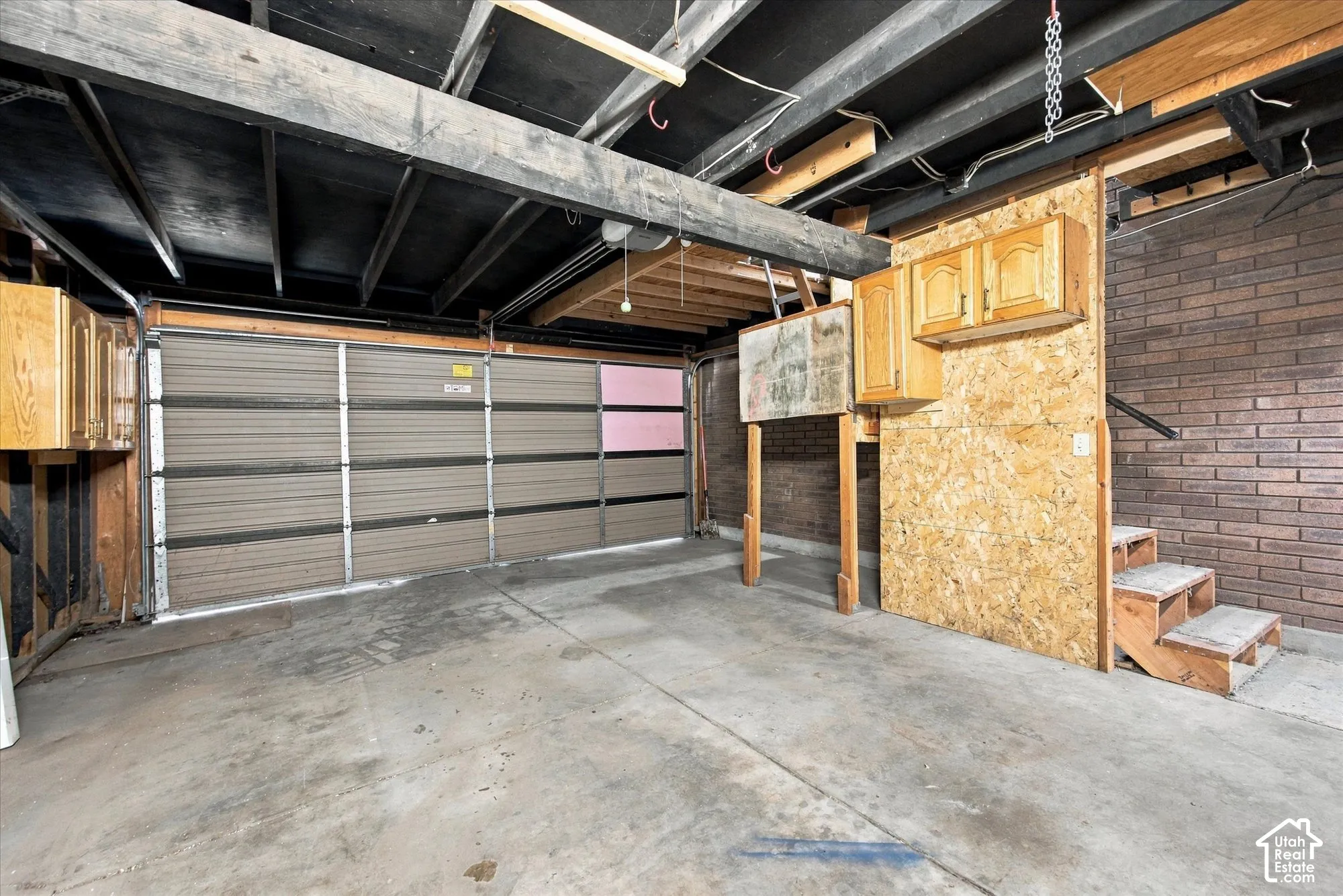 Concrete flooring, exposed ceiling joists, wood-finish cabinetry, and brick-look wall paneling