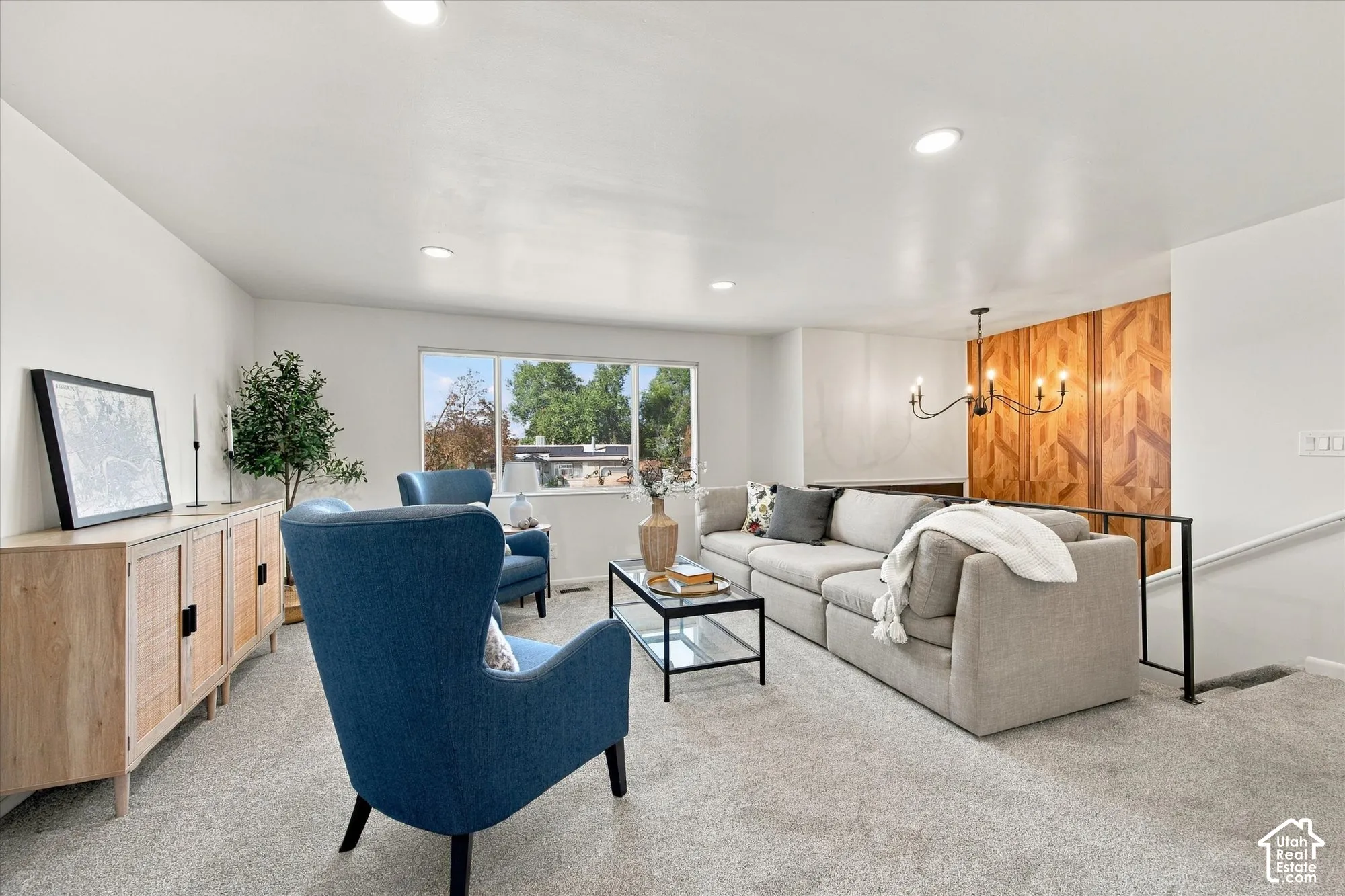 Recessed lighting illuminates the open living area featuring light-toned carpeting and a window offering abundant natural light