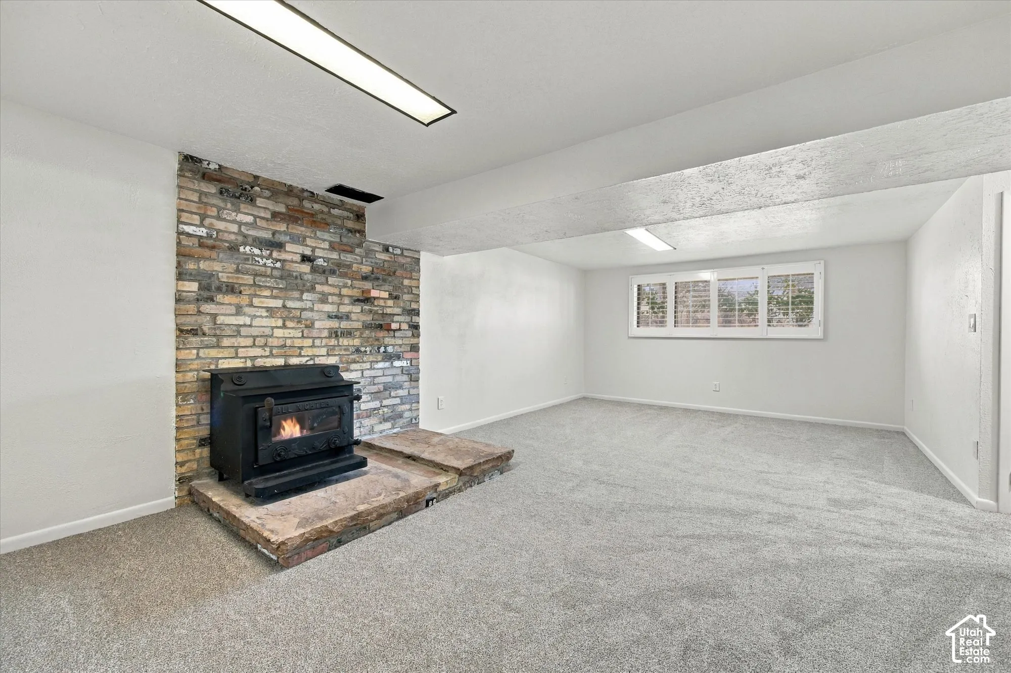 Brick accent wall featuring a wood-burning stove with a stone hearth