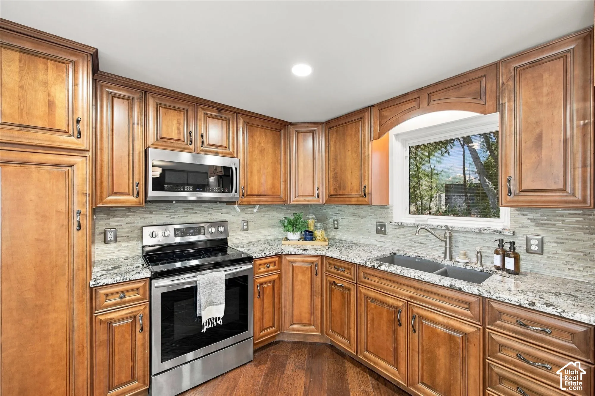 Kitchen featuring wood cabinetry, stainless steel appliances, granite countertops, and a tile backsplash