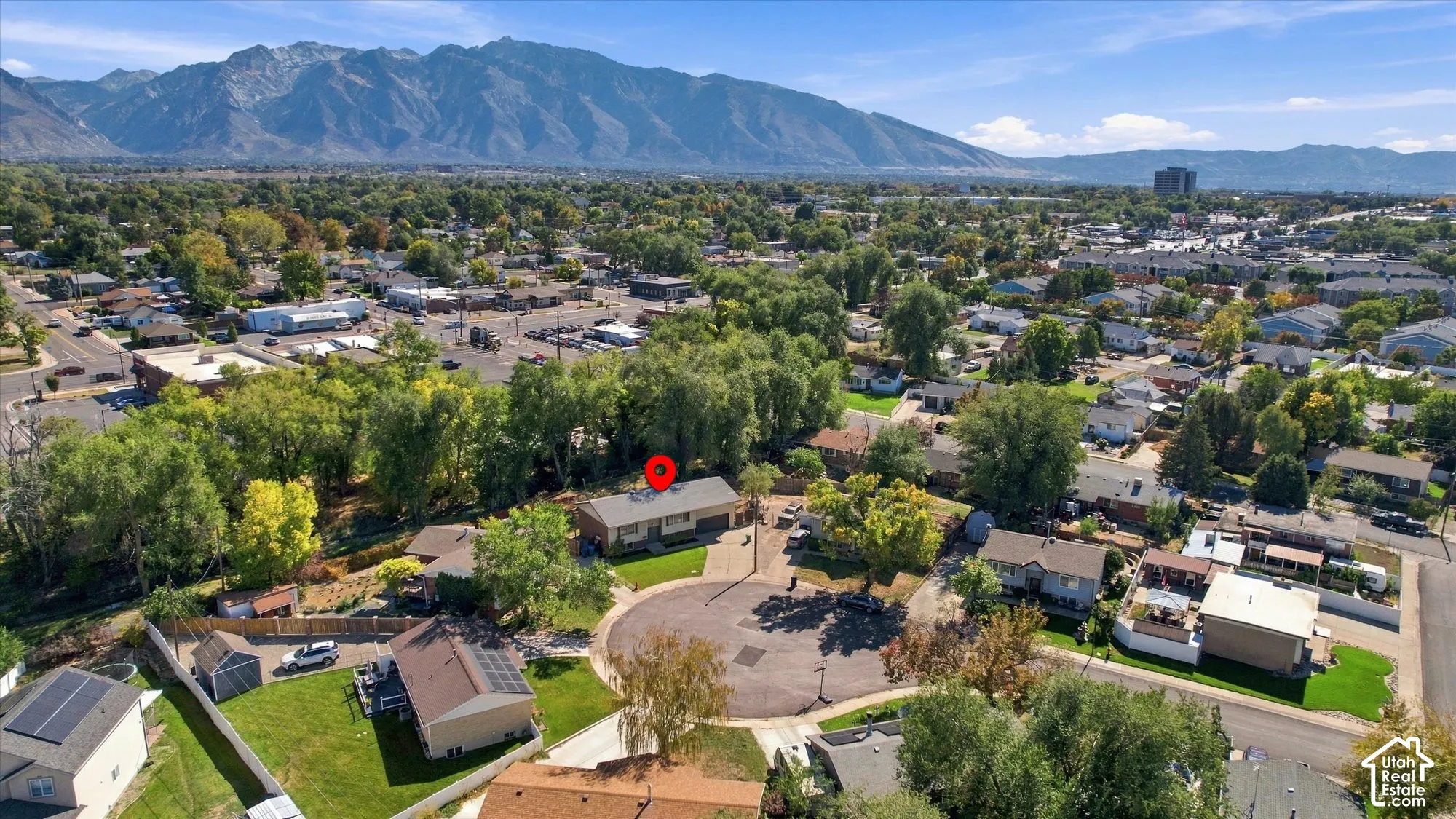 Residential property situated within a cul-de-sac, featuring a mountain backdrop and surrounding mature trees