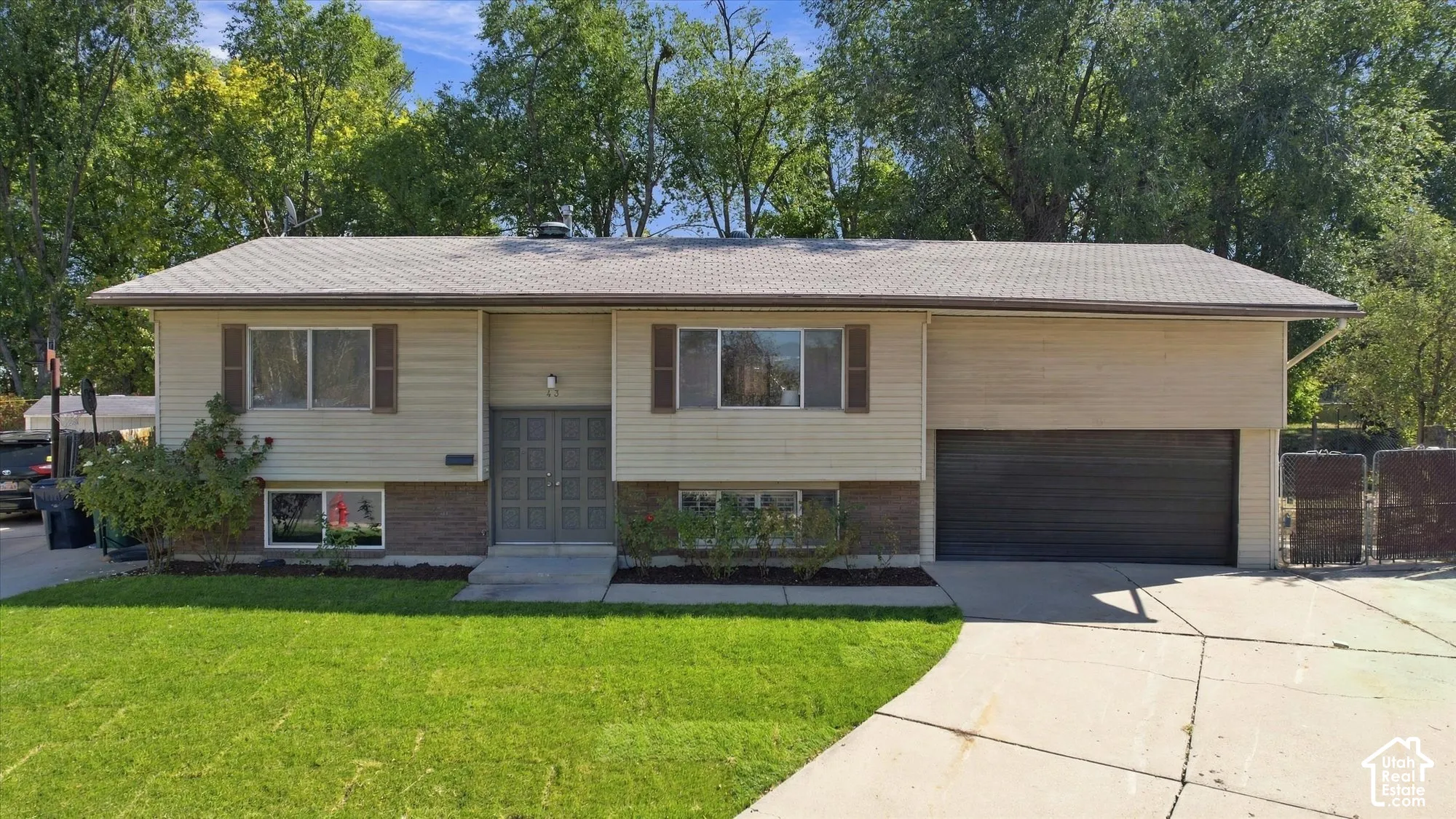 Split-level residence featuring a two-car garage, front yard landscaping, and a concrete driveway