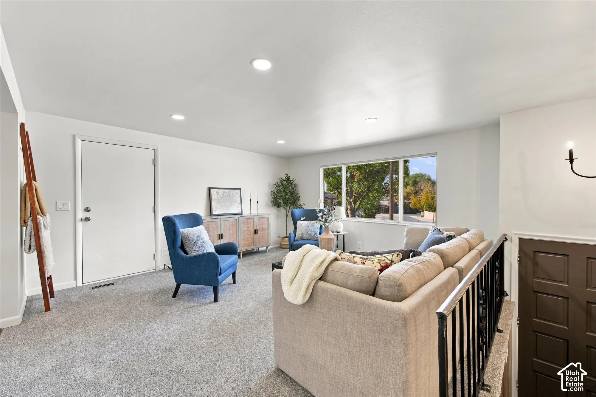 Recessed lighting, large window, carpeted flooring, white walls, black metal railing