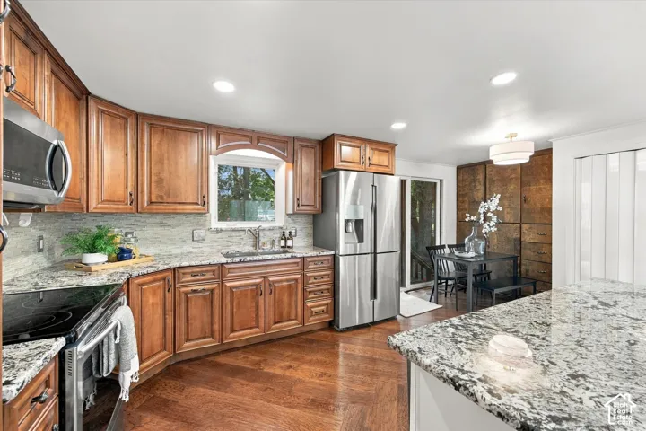 Wood-finish flooring with recessed lighting, granite countertops, stainless steel appliances, and wood cabinetry