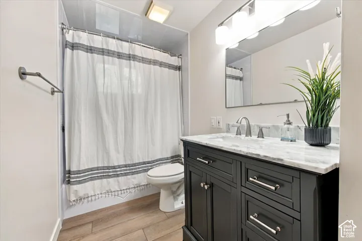 Dark wood vanity with a light-colored countertop, brushed nickel faucet, large mirror, and wood-finish flooring