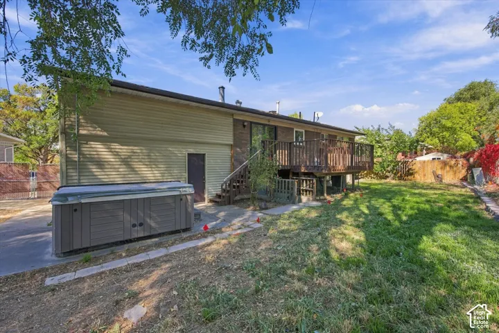 Rear exterior featuring a wood deck, sliding glass door, and a spa area