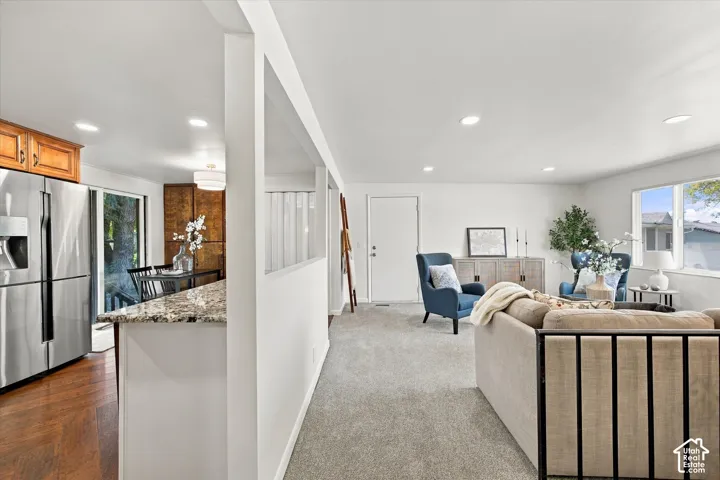 Open-concept living area with recessed lighting, light-toned carpeting, and large windows