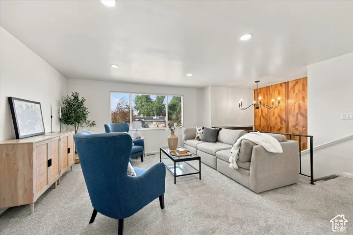 Recessed lighting illuminates the open living area featuring light-toned carpeting and a window offering abundant natural light