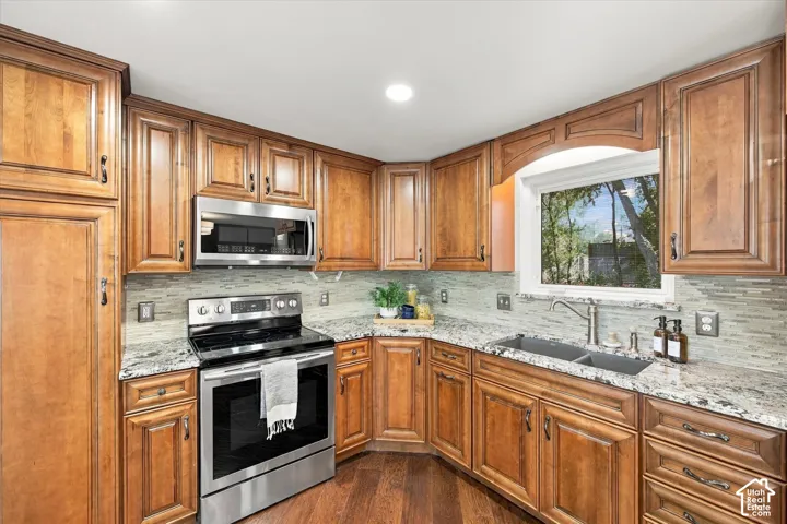 Kitchen featuring wood cabinetry, stainless steel appliances, granite countertops, and a tile backsplash