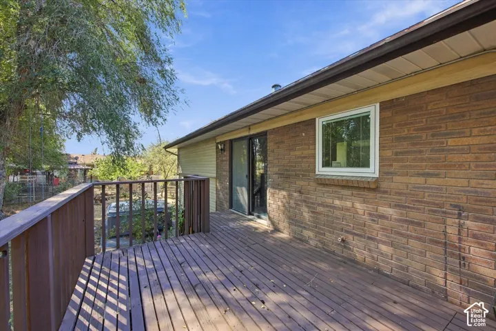 Wood-finish decking with coordinating railing, brick exterior, and a sliding glass door
