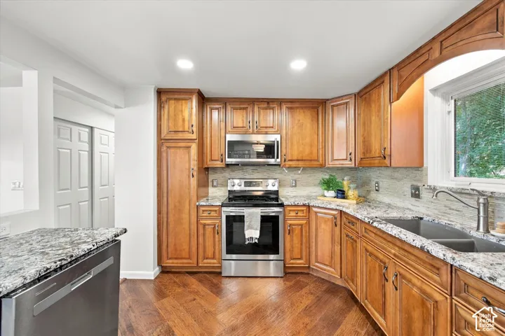 Hardwood flooring, stainless steel appliances, ample wood cabinetry, stone countertops, and a double basin sink