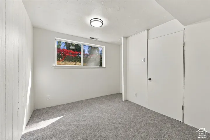 Carpeted room featuring a window, overhead light fixture, and white painted walls