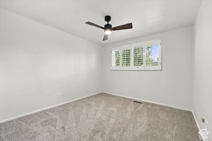 Plush gray carpeting, white walls, and a window with white plantation shutters