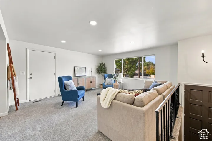 Recessed lighting, large window, carpeted flooring, white walls, black metal railing