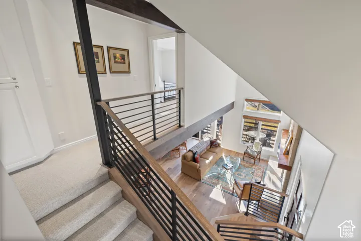 Loft area with carpeted flooring, built-in cabinetry, and a black metal and wood-finish railing