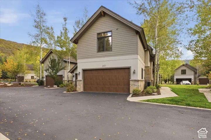 Multi-level exterior with board and batten siding, stone accents, and a wood-finish garage door