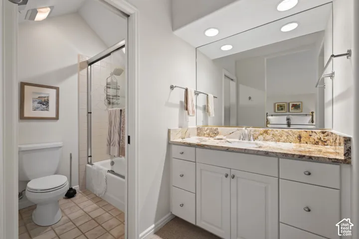 Bathroom featuring a spacious vanity with a stone countertop, an integrated sink, white cabinetry, a large mirror, and recessed lighting