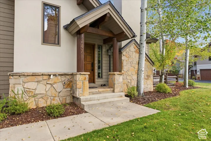 Stucco and stone exterior featuring a covered entry, wood-finish door, and integrated landscaping