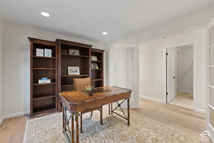 Recessed lighting, wood-finish flooring, white walls, and French doors