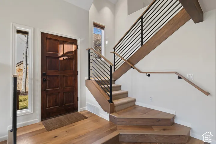 Wood-finish flooring, paneled entry door, vertical iron balusters, wood-finish stair treads, and recessed lighting