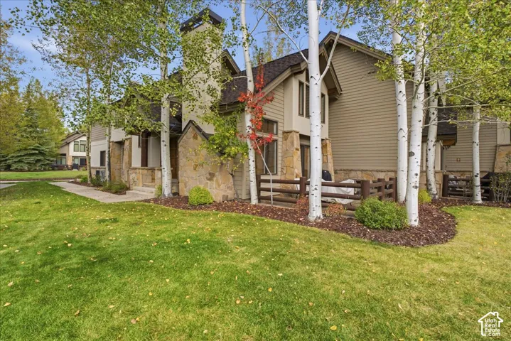 Stone veneer accents, multi-level structure, mature trees, landscaped beds, and a manicured lawn