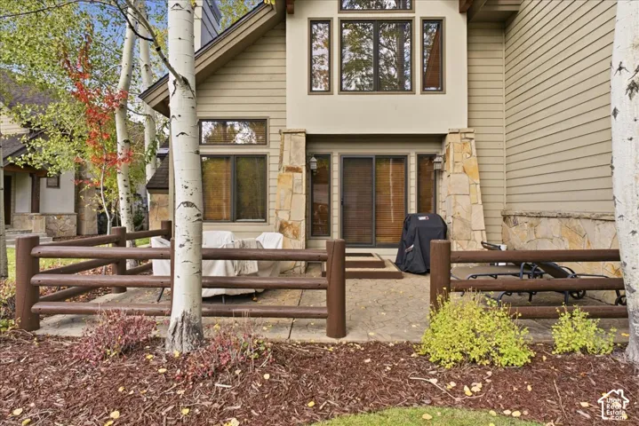 Exterior featuring horizontal siding, stone accents, and a stone patio