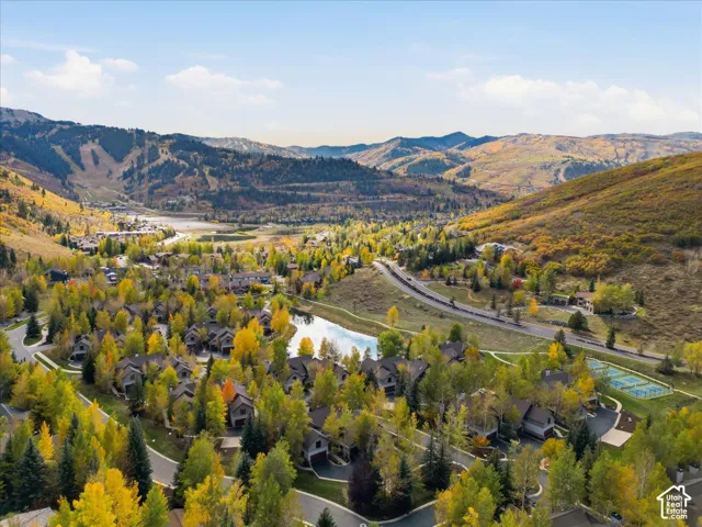 Mountain community setting with multiple residences, extensive green spaces, a discernible tennis court, and natural water features