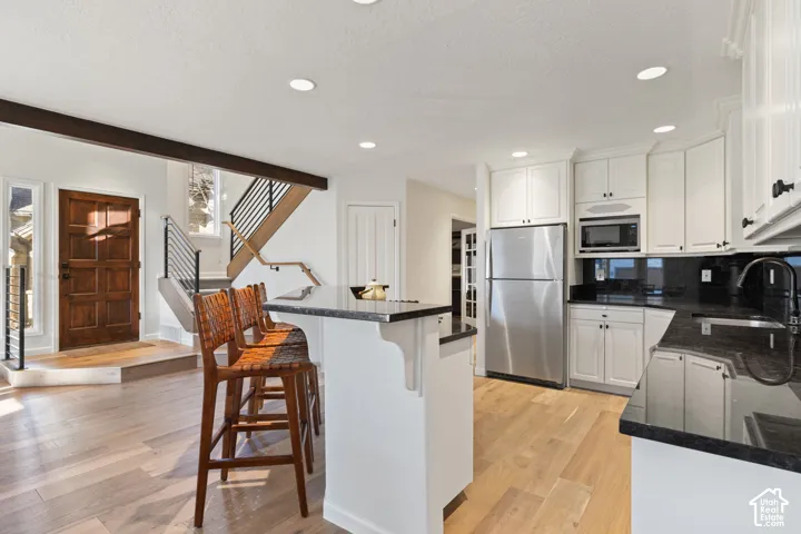 Kitchen with white shaker-style cabinetry, dark stone countertops, and stainless steel appliances
