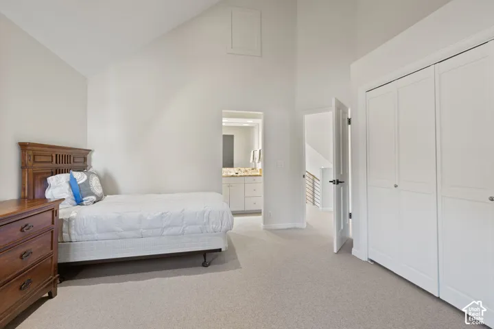 Vaulted ceiling, neutral carpet, bi-fold closet doors, and recessed vanity with a stone-finish countertop