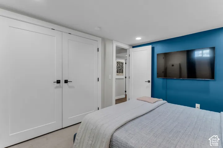 Recessed lighting illuminates the space, featuring a wall-mounted television and two paneled doors with black hardware