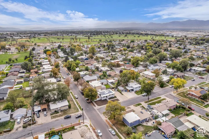 Residential neighborhood with mature trees, paved streets, and distant mountain backdrop