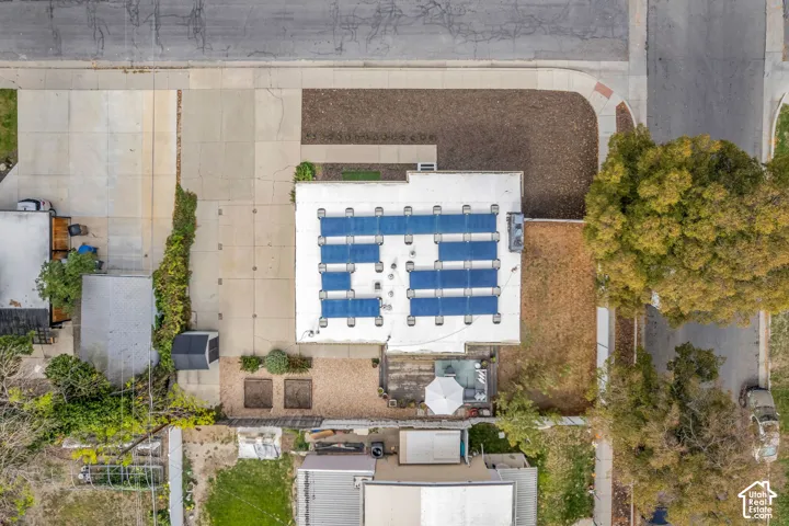 Rooftop solar panels, expansive concrete driveway, gravel patio area, and raised garden beds