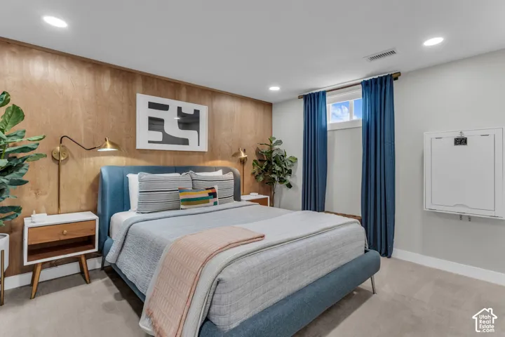 Wood-paneled accent wall, recessed lighting, wall-mounted sconces, and neutral carpeting