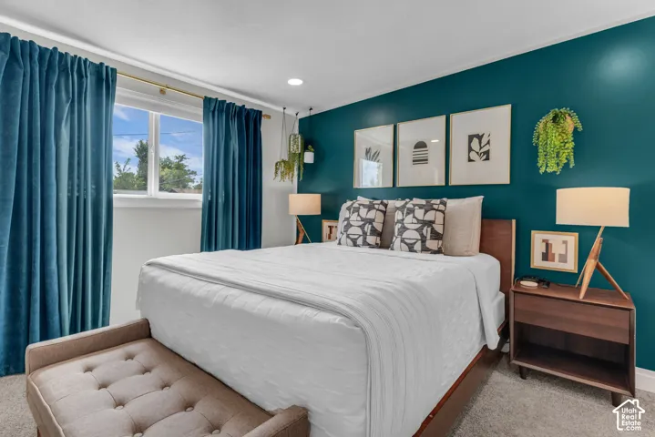 Recessed lighting, wood-finish bed frame, light-colored carpeting, window with natural light, and a rich teal accent wall