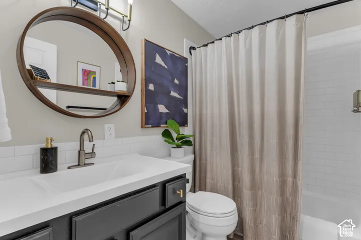White subway tile backsplash, dark-finish vanity with white countertop, round wood-frame mirror with integrated shelf, and an overhead vanity light fixture