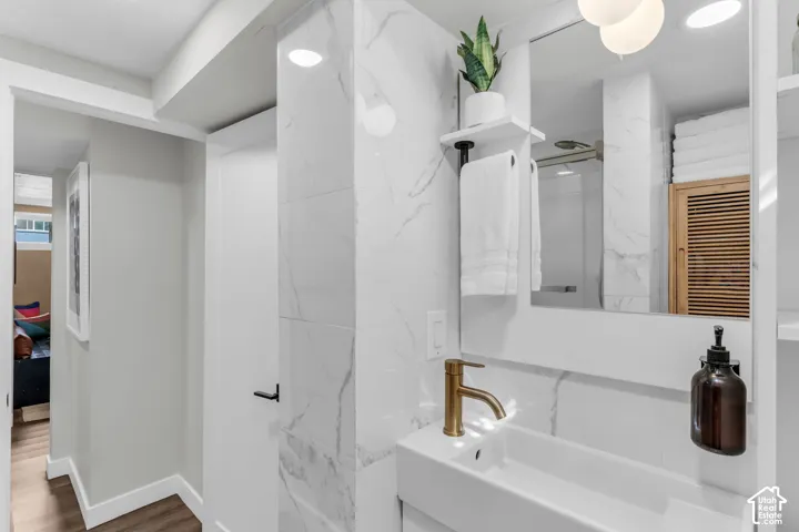 White rectangular sink with a brass-finish faucet, full-height wall tiling, and a recessed shower enclosure